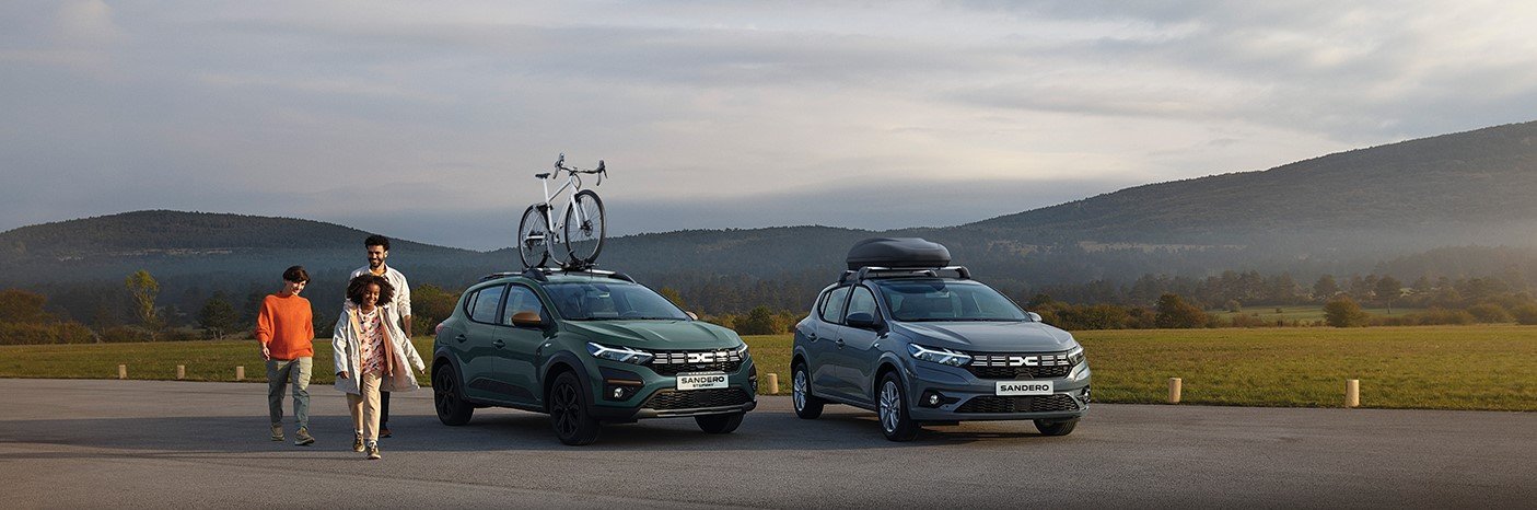 Familie mit zwei Autos in der Natur, eines mit Fahrradträger, das andere mit Dachbox.