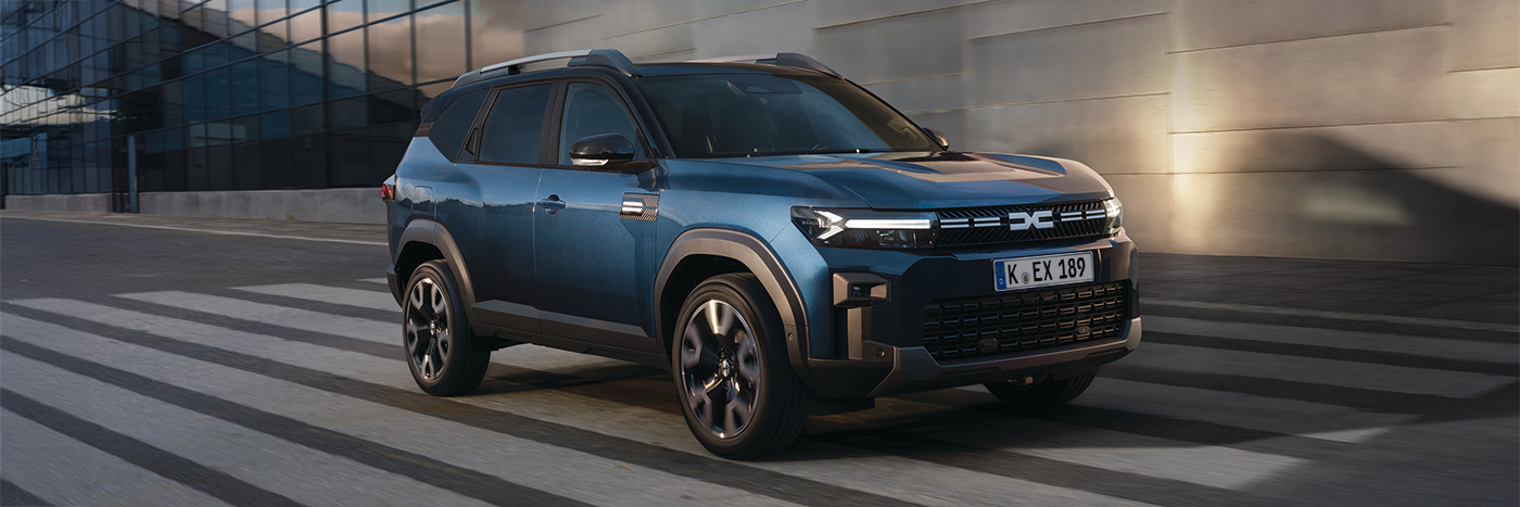 Blauer SUV fährt über Zebrastreifen vor modernem Gebäude, im urbanen Umfeld.