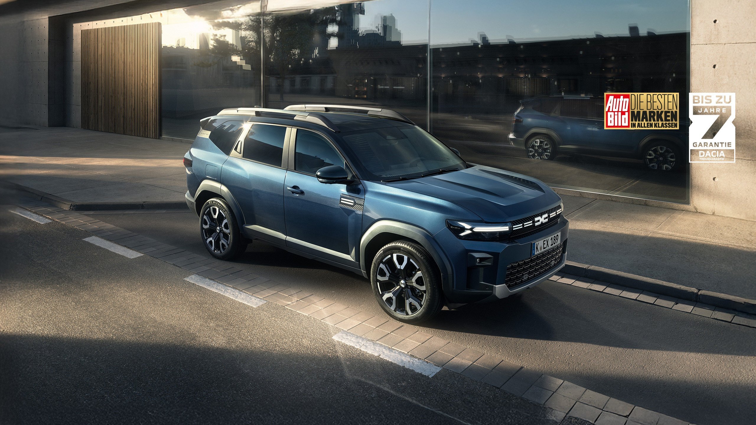 Ein blauer SUV parkt auf einer modernen Stadtstraße mit reflektierenden Fenstern im Hintergrund.