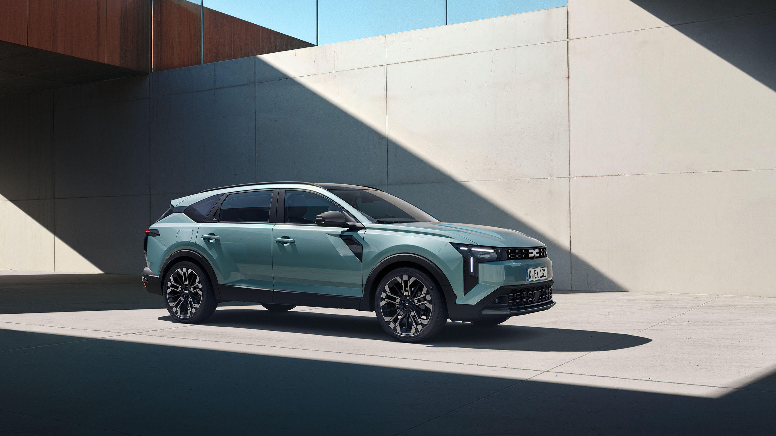 Ein modernes SUV in mintgrüner Farbe steht vor einer minimalistischen Betonwand mit Schattenwurf.