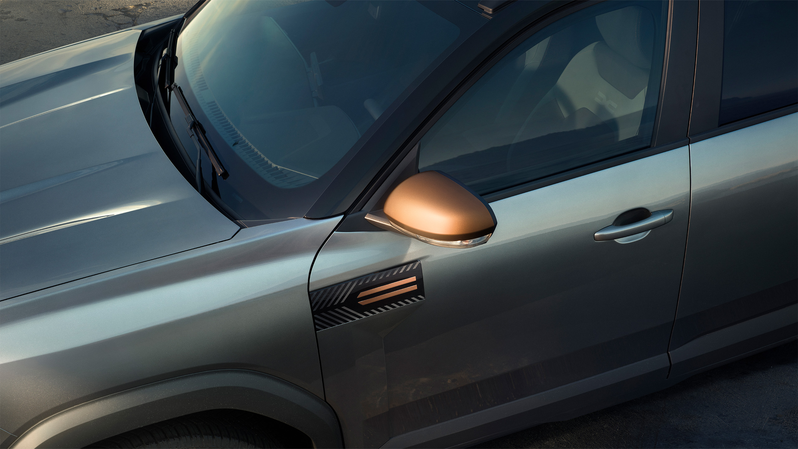 Nahaufnahme eines modernen Fahrzeugs, das silberne Farbe und einen bronzefarbenen Außenspiegel zeigt.