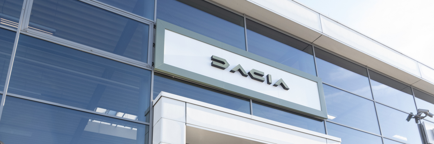 Fassade eines modernen Autohauses mit dem Dacia-Schild, gut beleuchtet bei Tageslicht.