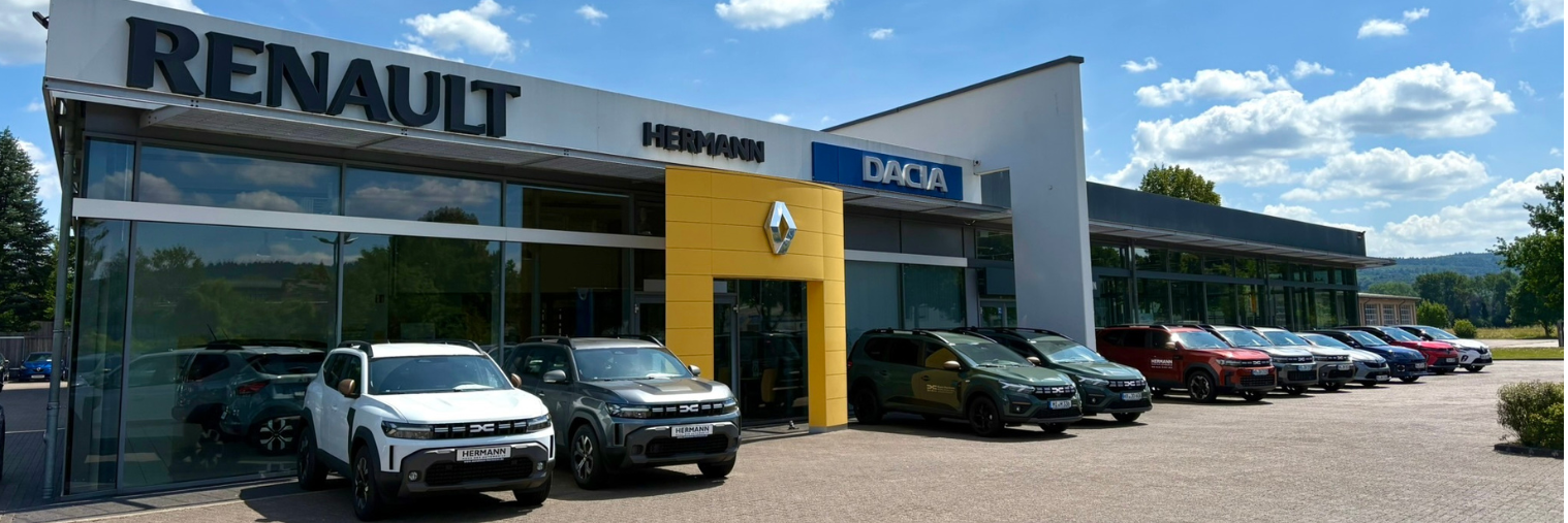 Renault und Dacia Autohaus mit verschiedenen Fahrzeugen auf dem Parkplatz an einem sonnigen Tag.