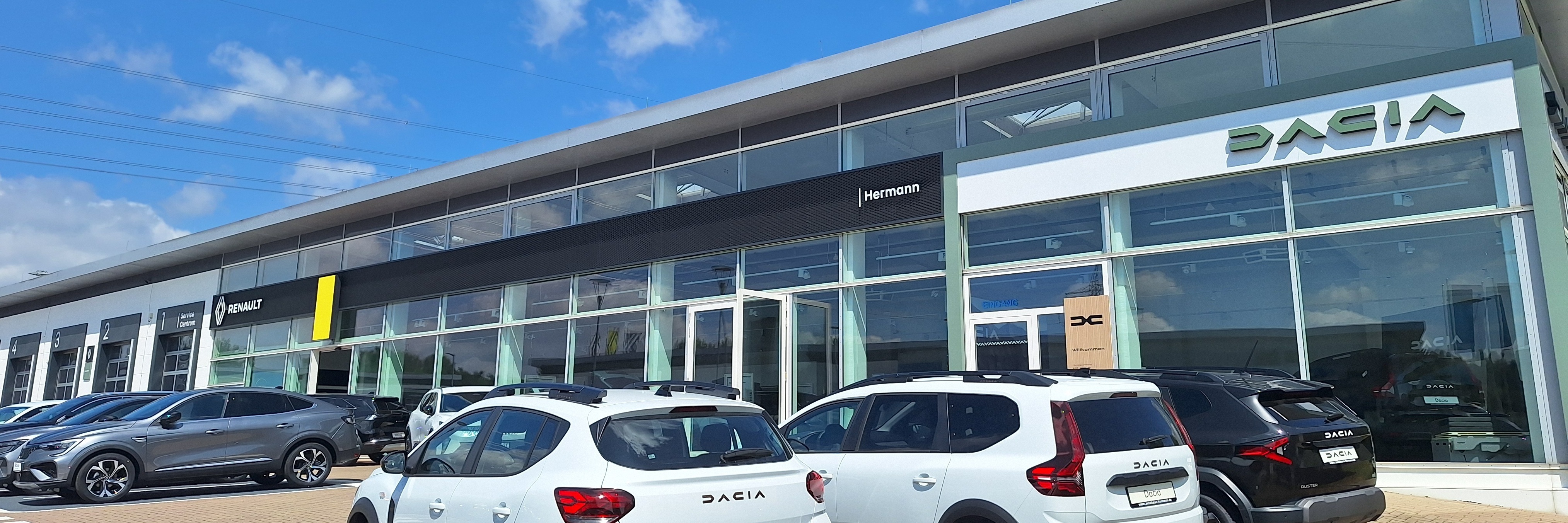 Autohäuser mit Dacia und Renault Fahrzeugen unter klarem Himmel, modernes Design.