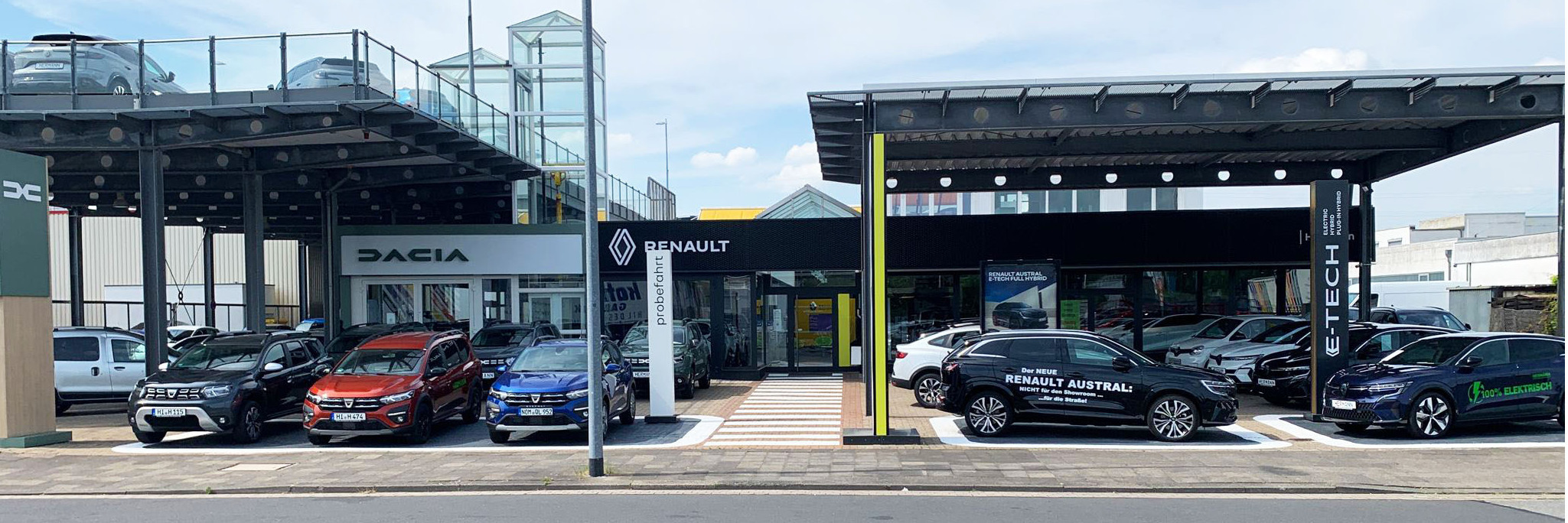 Renault und Dacia Autohaus mit verschiedenen Autos auf dem Parkplatz, moderne Architektur und Sonnenschein.