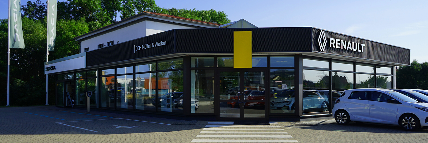 Renault Autohaus von außen mit großen Fenstern, gelben Akzenten und geparkten Autos auf dem Gelände.