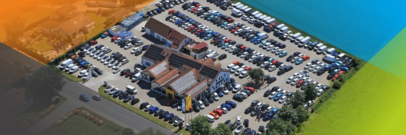 Luftbild eines großen Parkplatzes mit vielen Autos und einem Gebäude in der Mitte.