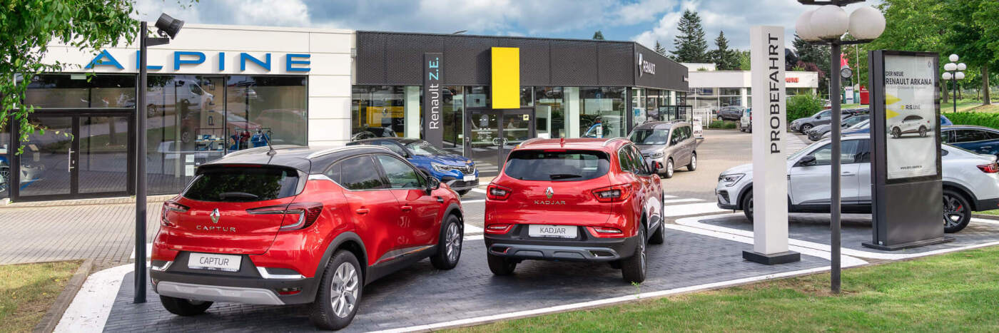 Zwei rote Autos, Renault Captur und Kadjar, vor einem Autohaus mit der Aufschrift Alpine und Renault Z.E.