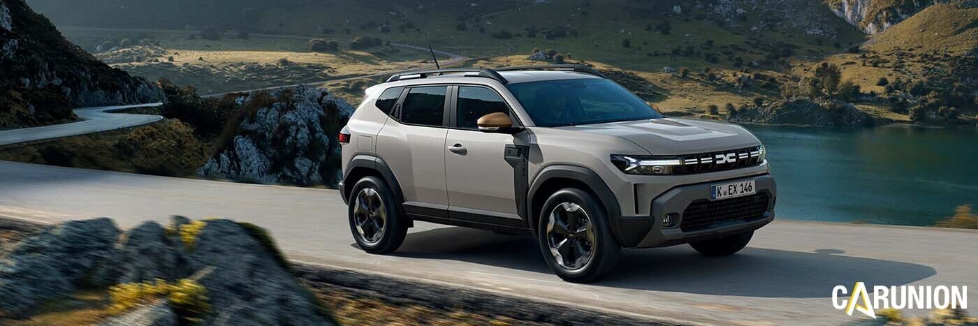 Ein moderner SUV fährt an einem malerischen See entlang, umgeben von grünen Hügeln und felsigen Landschaften.