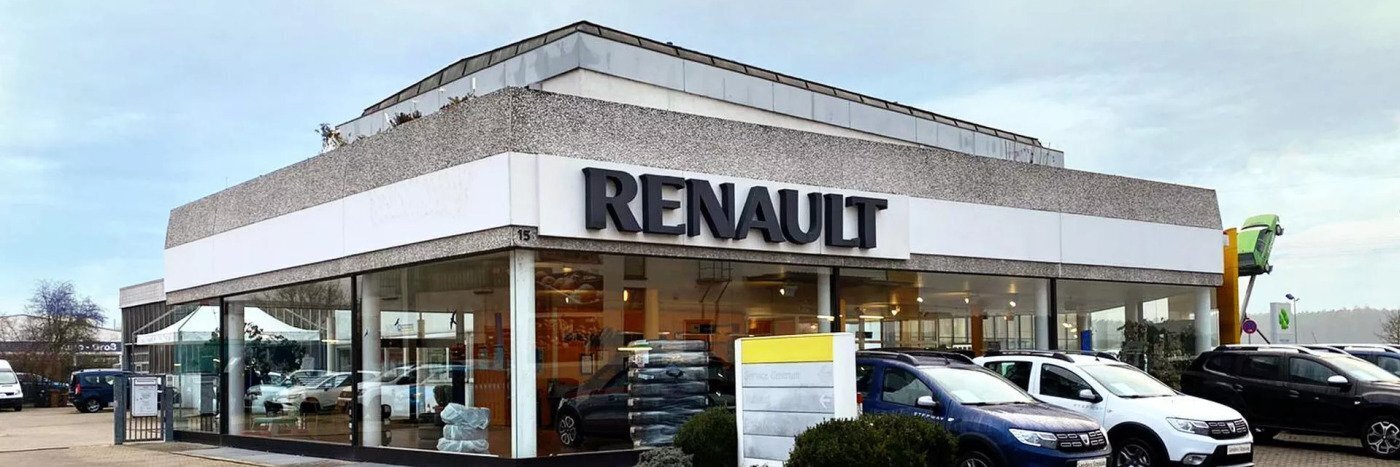 Renault-Autohaus mit modernem Design und verschiedenen Fahrzeugen auf dem Parkplatz.