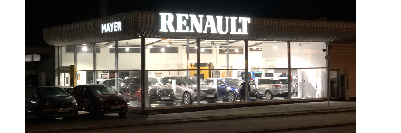 Renault Autohaus Mayer bei Nacht mit mehreren Autos sichtbar durch große Fenster.