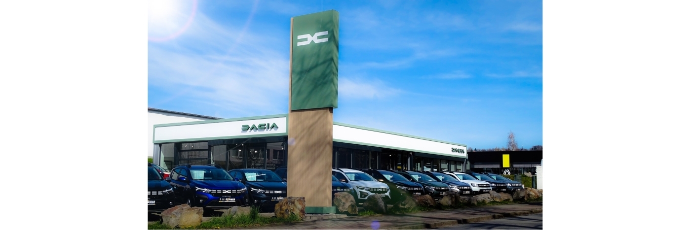 Dacia Autohaus mit mehreren Fahrzeugen vor dem Gebäude und einem hohen Firmenschild.
